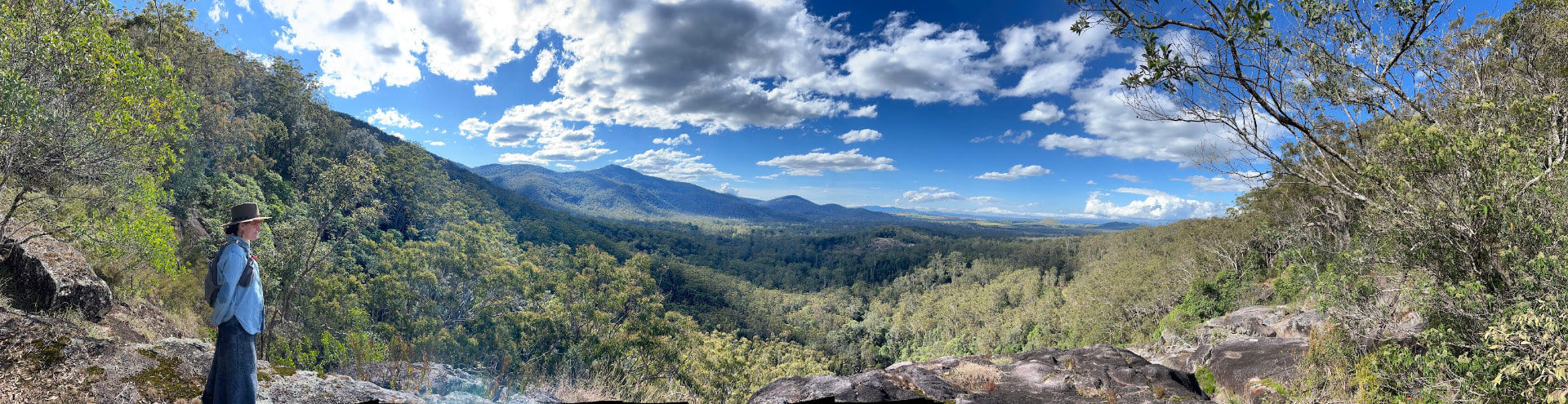 Holly standing on a rocky outcrop looking out over forested valleys in Queensland